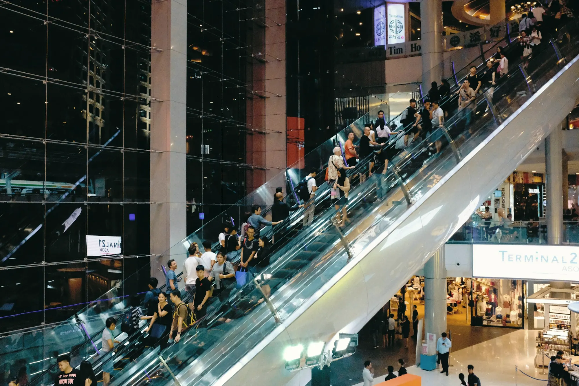 Shoppers riding escalators in a busy shopping centre